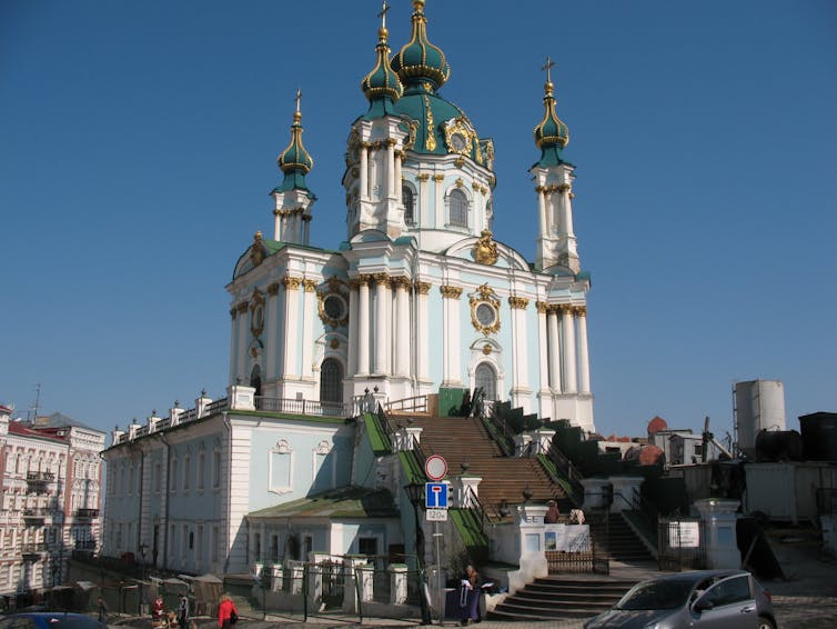 A blue and white church with gold detail on the roof and many steps leading up to it.