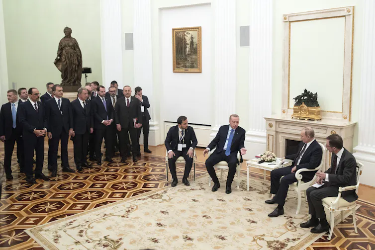 A statue of a woman is seen behind a meeting of men.