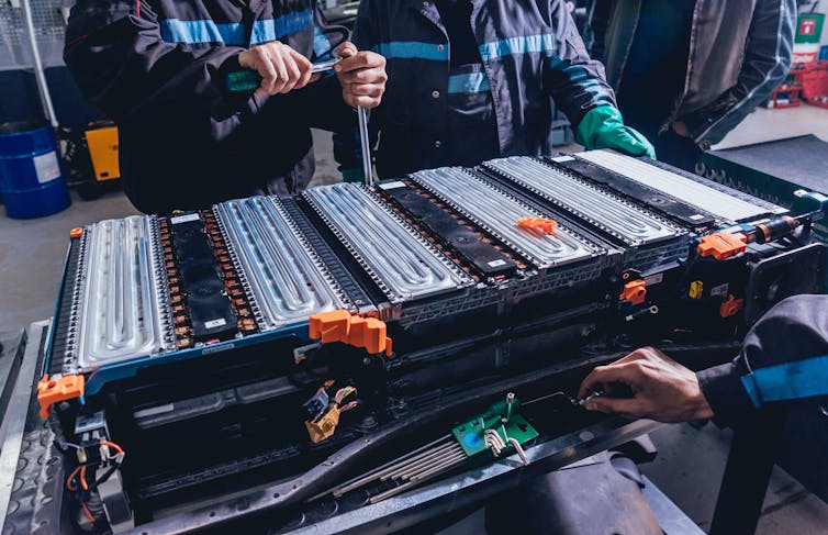 Engineers stand around a large battery.