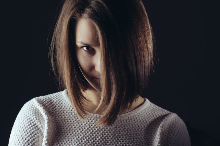 Portrait of woman, with her face partly covered by her hair.