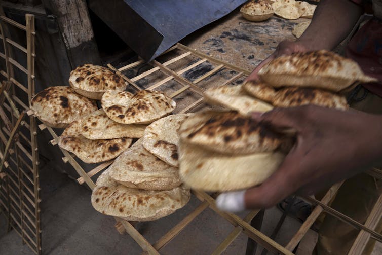 Round flatbreads cool on a rack in a bakery.