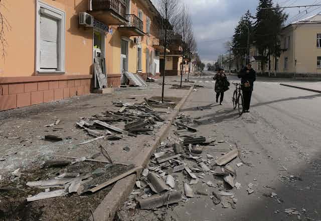 Two people walk along a street destroyed by shelling in Chernihiv, northern Ukraine
