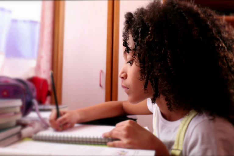 Girl doing homework writing in notebook
