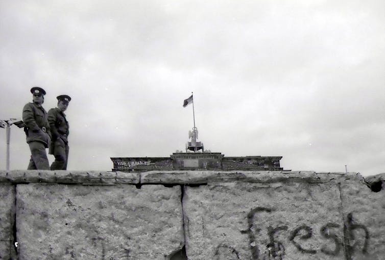 Two guards patrol the Berlin Wall.