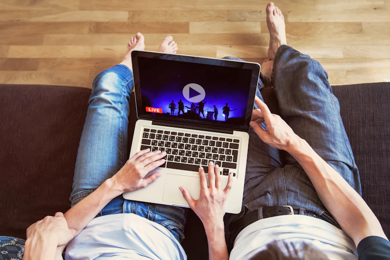 A couple sit on a couch, streaming a concert