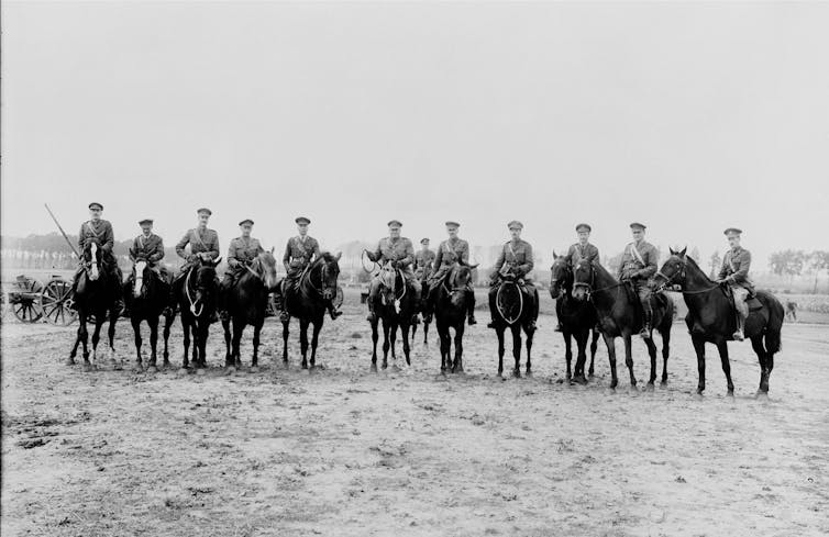 A line of horses and riders in a black and white photograph.