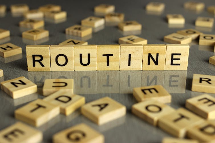 Scattered scrabble tiles, with seven standing tiles reading 'routine'