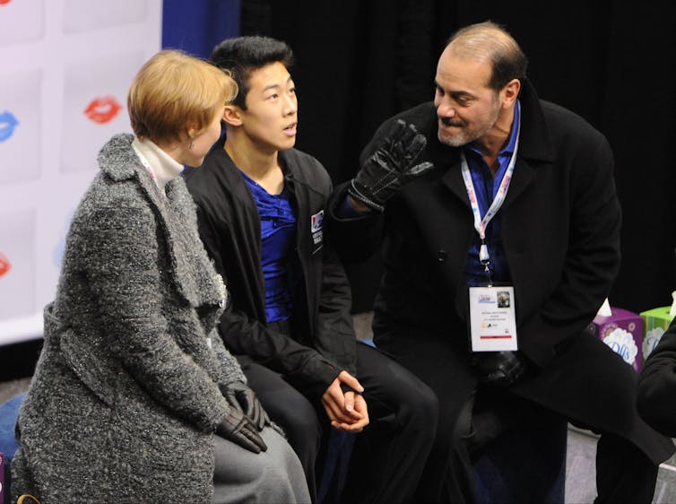 An Asian American man sits between a woman and a man.