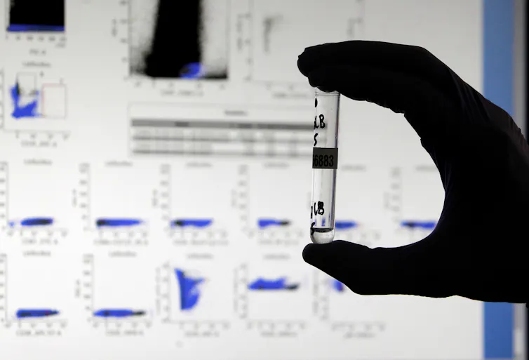 hand holds testtube with graphs in background