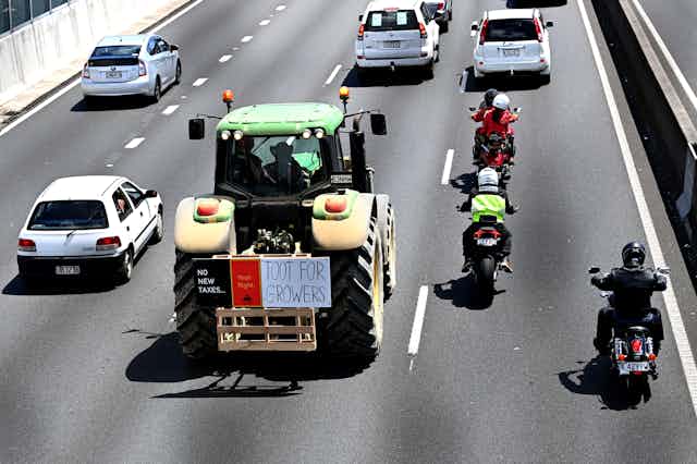 Green and yellow tractor with protest sign driving down the motorway. 