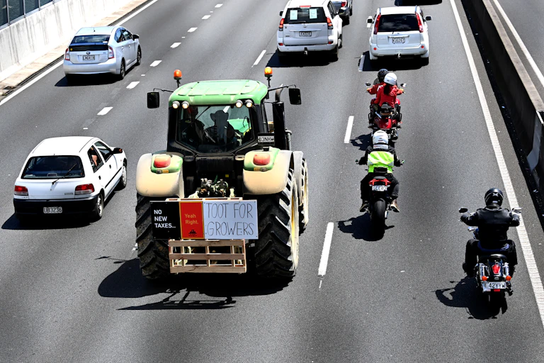 Green and yellow tractor with protest sign driving down the motorway.