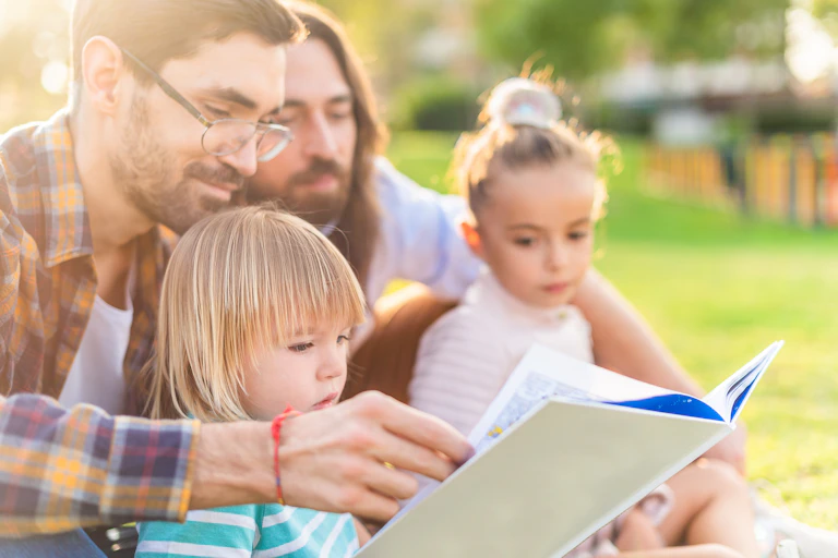 two men reading a book with two young children