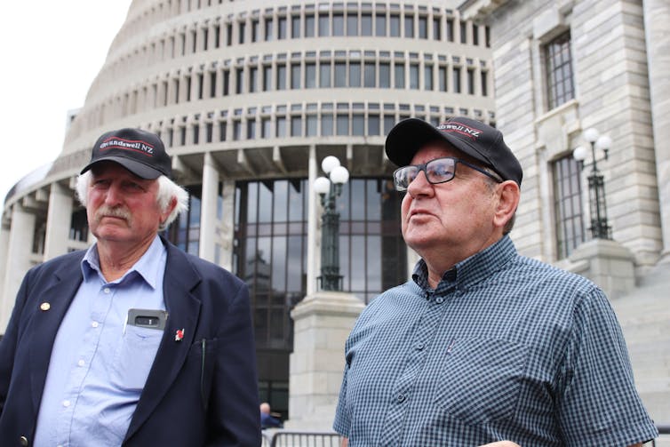 Two farmers with hats in front of New Zealand's parliament.