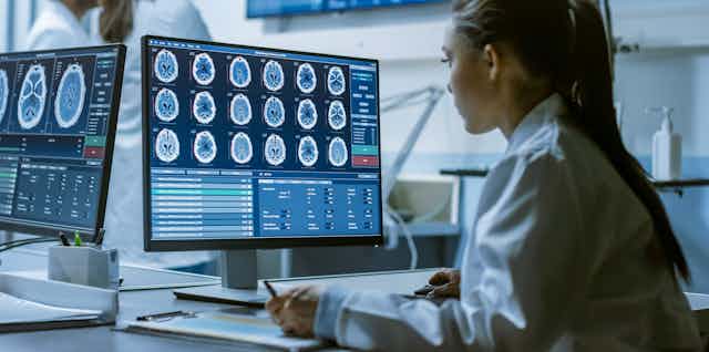 Scientist looking at brain scans on screen.