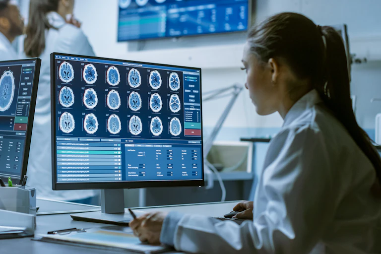 Scientist looking at brain scans on screen.