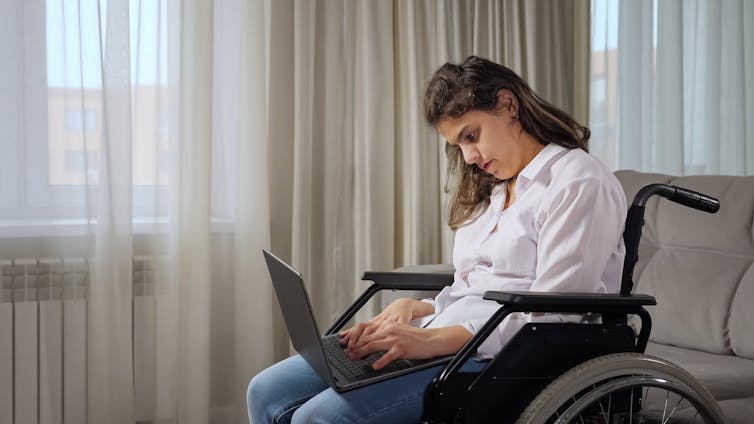 Woman with cerebral palsy types on her laptop.