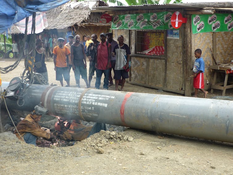 people watch as man works on concrete pipe