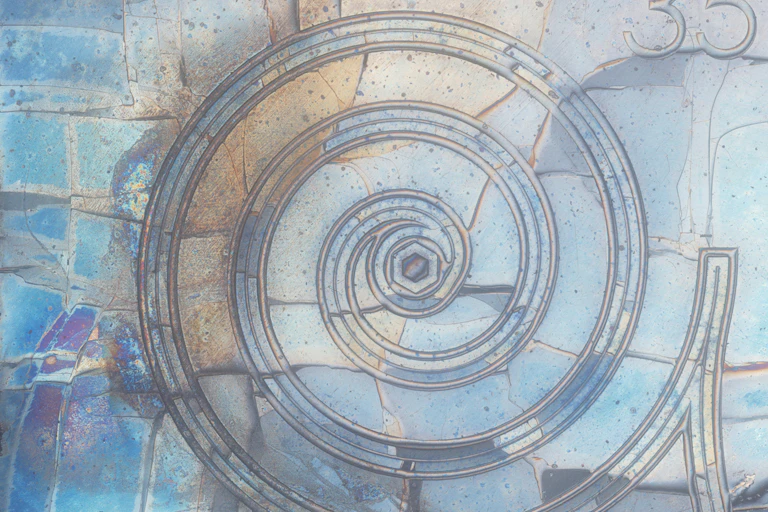 Spirale en relief à la surface d'une plaque ressemblant à du verre ; la plaque est également parcourue de nombreux traits irréguliers