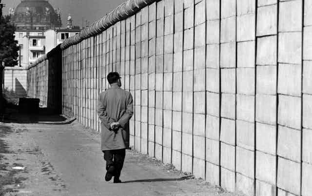 A man walks past the Berlin Wall.