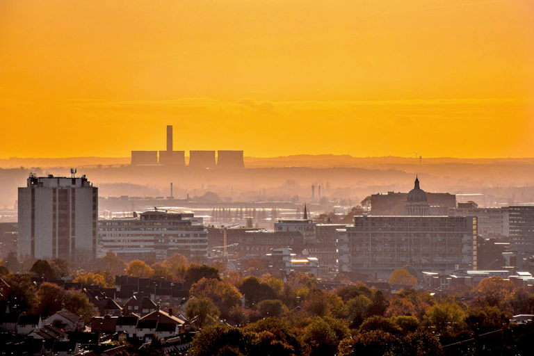 A cityscape against a yellow sky with a power station in the background.