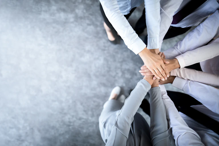 Close up top view of business people putting their hands together to signify trust and unity