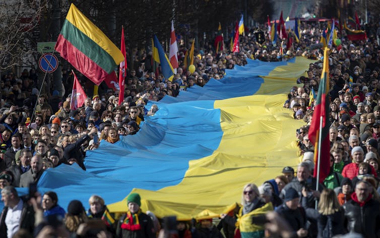 A sea of people carry a massive Ukrainian flag.