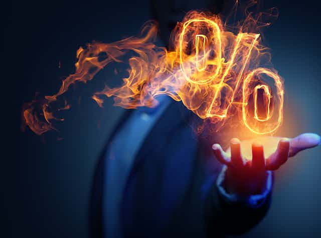 A man with his hand out and a flaming percentage sign above his palm