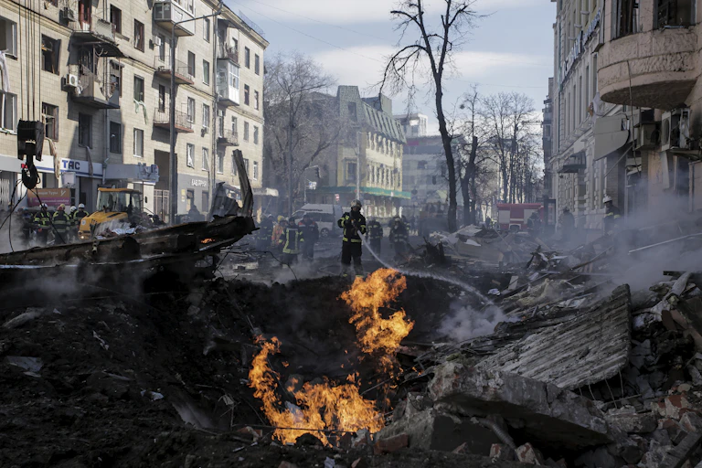 Firefighters spray water on a fire amid a heap of rubble.