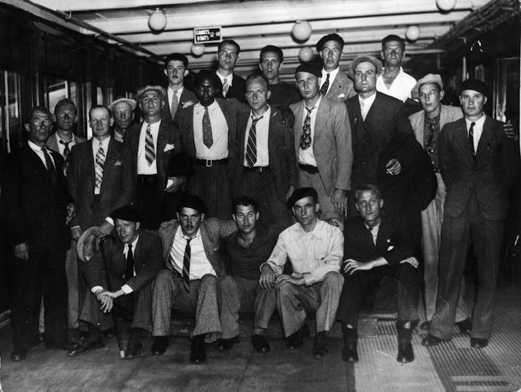 Group of men in suits pose on a ship.