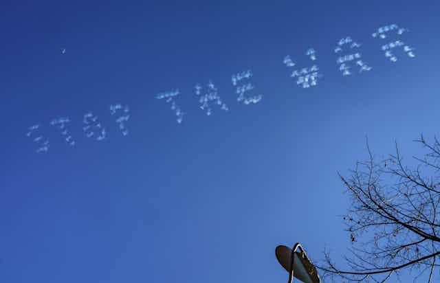 The words "stop the war" are written against a clear blue sky