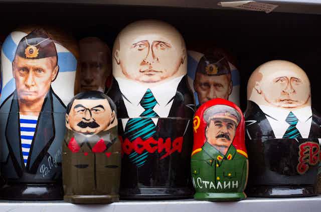 Three different Putin dolls are lined up along with two Stalin dolls