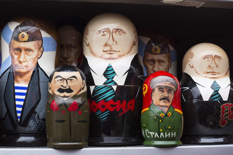 Three different Putin dolls are lined up along with two Stalin dolls