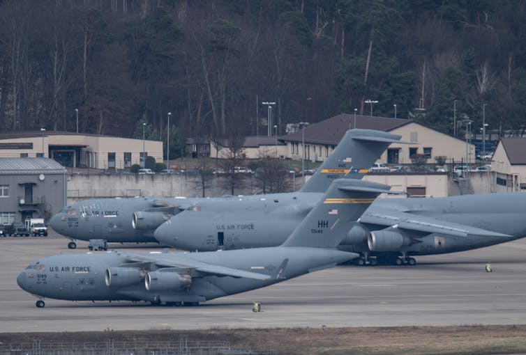 Three large U.S. Air Force plans are shown on a tarmac.