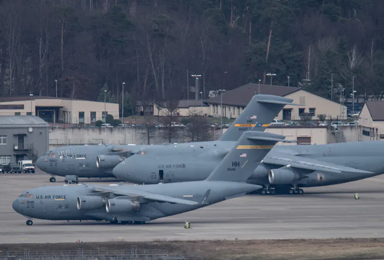 Three large U.S. Air Force plans are shown on a tarmac.