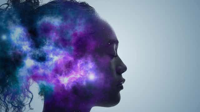Profile of person with eyes closed, a purple and blue galaxy superimposed on the back of their head