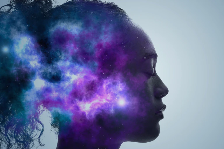 Profile of person with eyes closed, a purple and blue galaxy superimposed on the back of their head