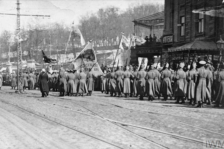 A black and white photo depicts Ukrainian soldiers marching while holding aloft flags.