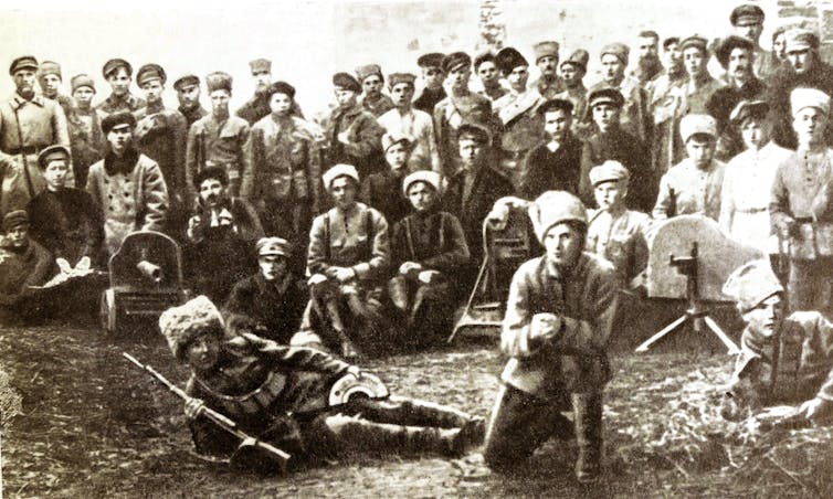 A group of men in uniform pose with weapons in a grainy photograph