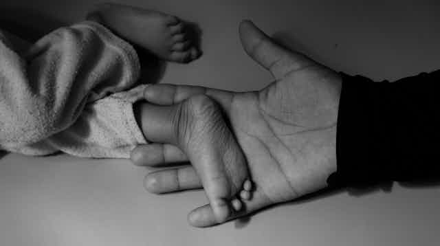 A woman holds a child's tiny foot in her hand.