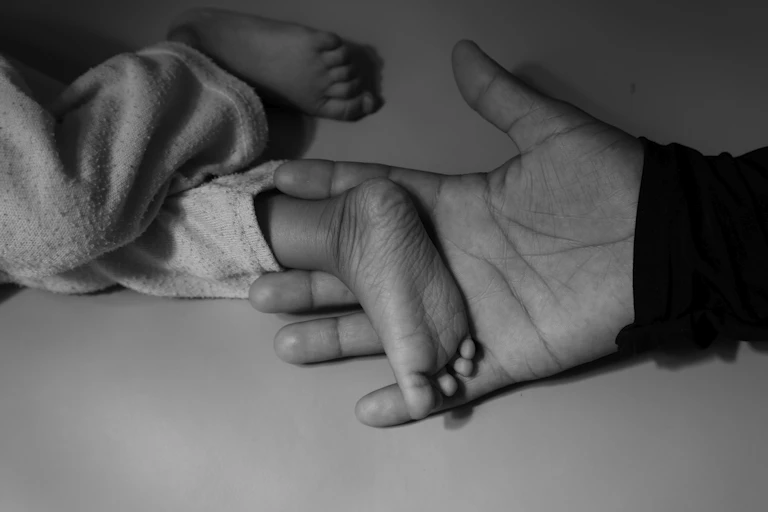 A woman holds a child's tiny foot in her hand.