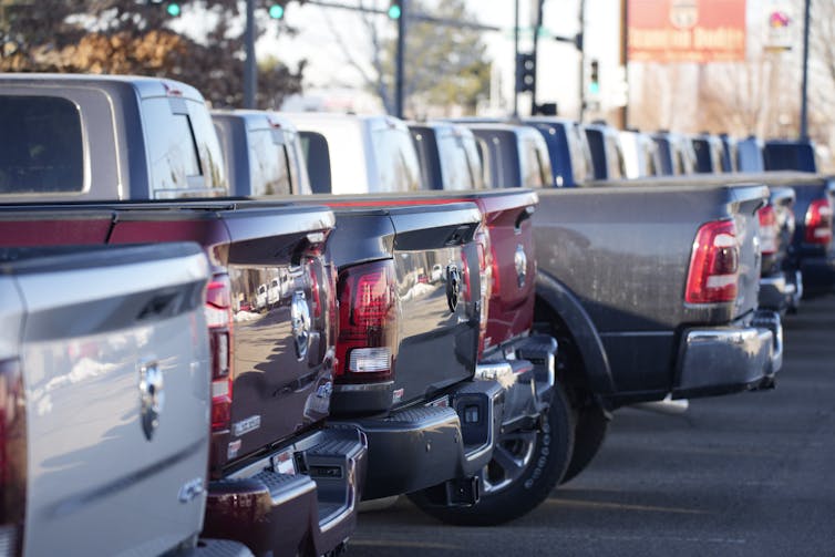 The rear ends of new pickup trucks in a colorful assortment are lined up
