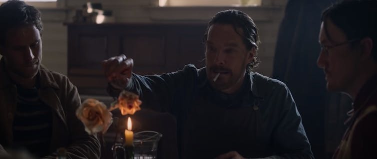 A man is seen lighting a paper flower on fire.