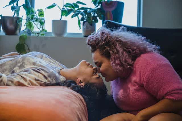 A couple sit with their heads close together.