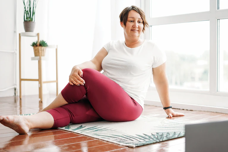 Middle aged woman stretches in her loungeroom