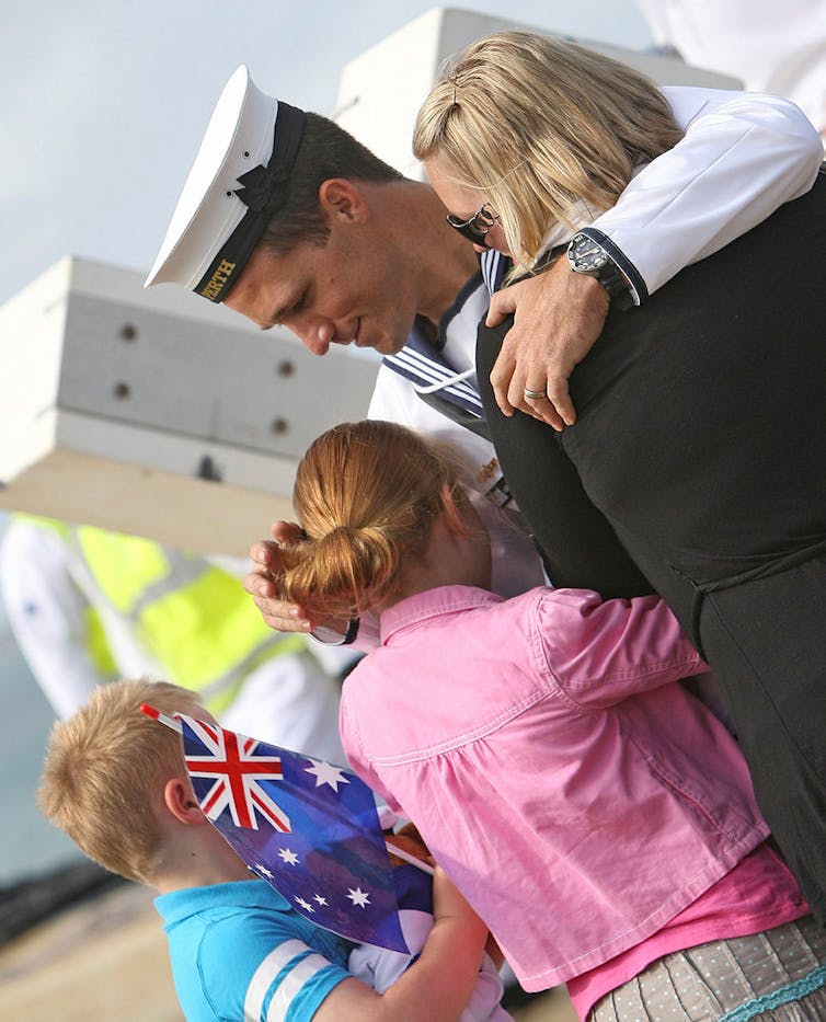 Sailor hugging family members after deployment ends