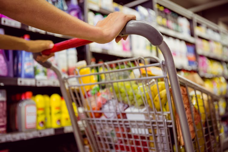 Woman pushes a shopping trolly of healthy food.