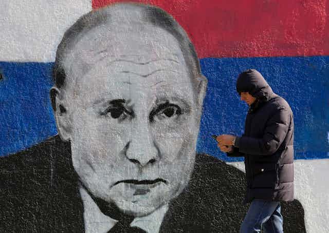 A man passes by a mural depicting the Russian President Vladimir Putin in Belgrade