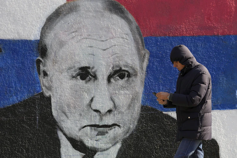 A man passes by a mural depicting the Russian President Vladimir Putin in Belgrade