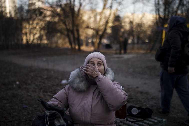 A woman reacts after being rescued by firefighters from her apartment in a burning building that was hit by artillery shells in Kyiv