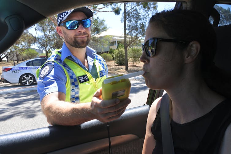 A woman taking a roadside breath test.